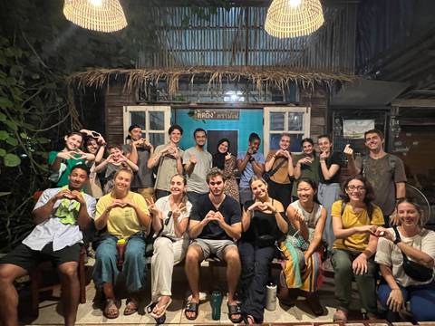 A large group of people sitting together, forming heart shapes with their hands.
