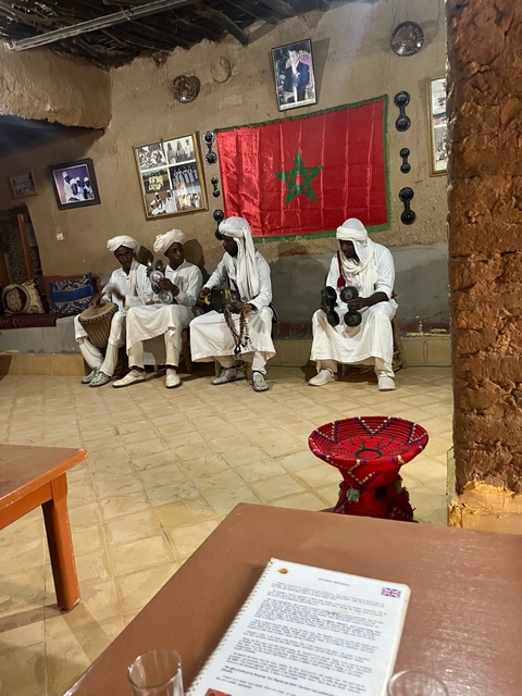 A group of traditional musicians wearing white robes and turbans.