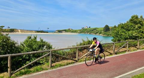 A cyclist riding by a beachside road.