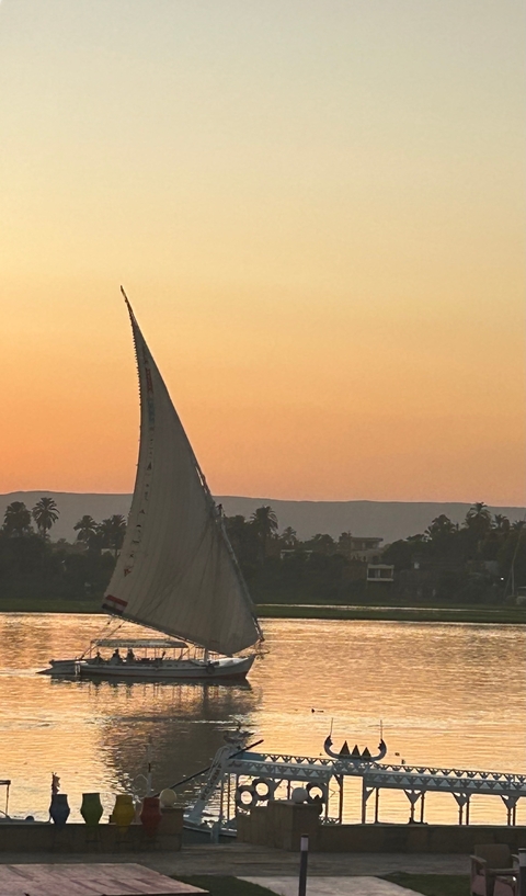 Sailboat in silhouette against a sunset over water.