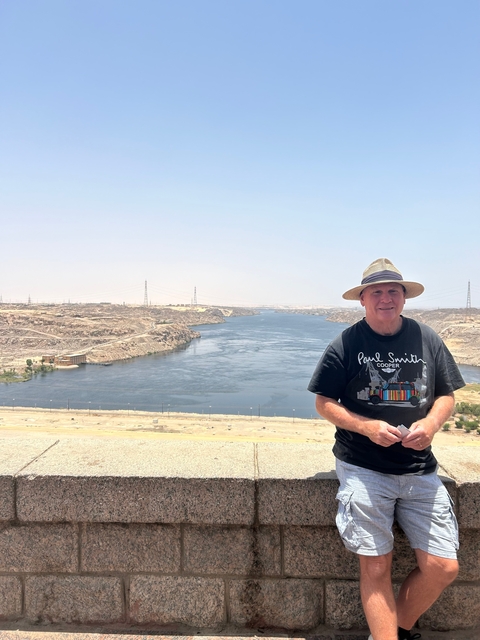 A man standing next to a river with a vast landscape.