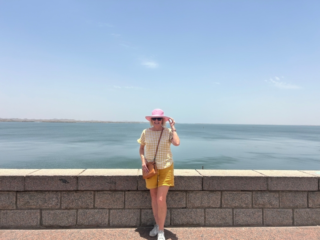       A woman posing in front of a large water body.
  