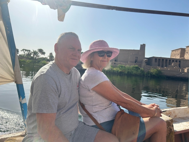 A couple on a boat with an ancient stone temple in the background.