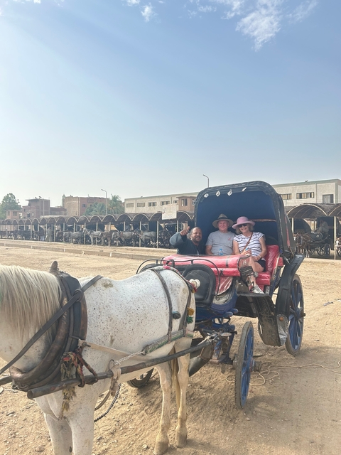       A couple in a horse-drawn carriage waving.
  