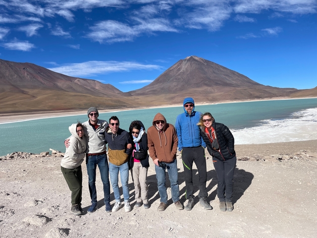 Group of people posing by a lake in the mountains.