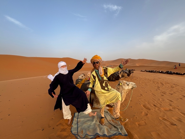 Two people on camels in the desert.