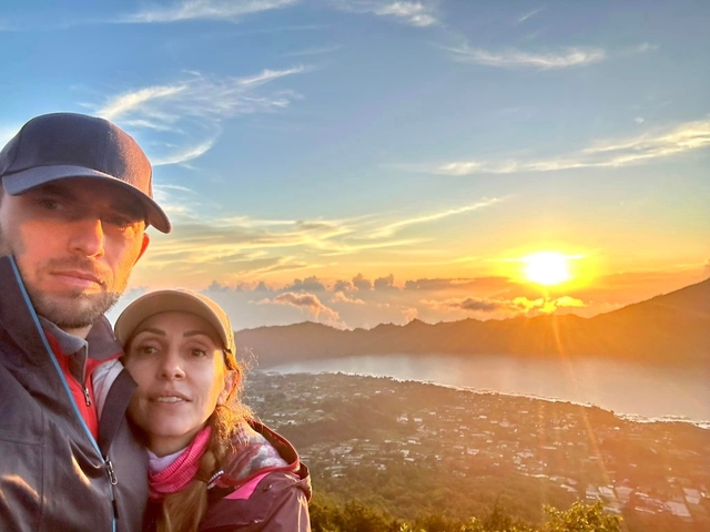       Couple posing with a sunrise view and water body in the background.
  