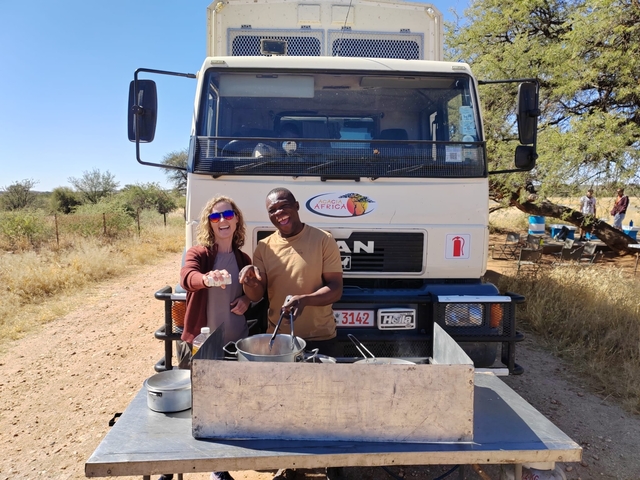 Two people cooking in front of a truck with a Locas Africa logo.