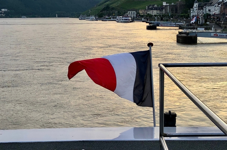 French flag on a ship with river in the background.