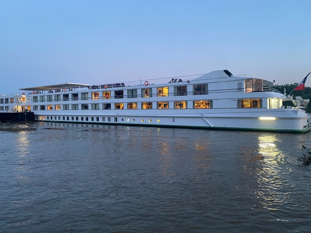 Large cruise ship on a river during dusk.