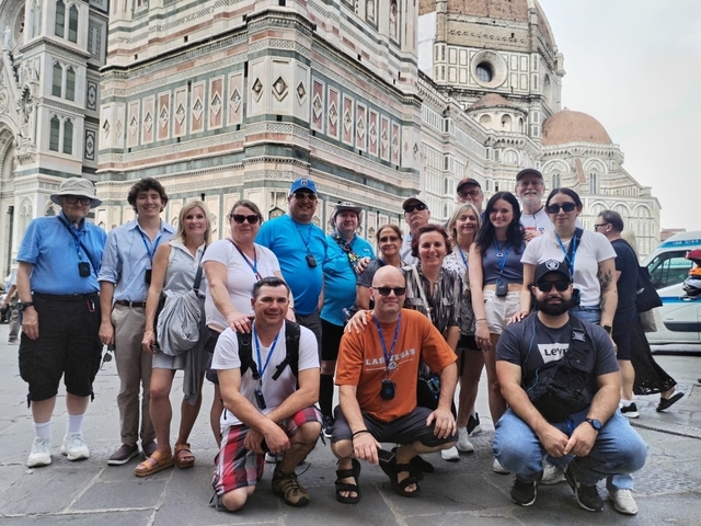 Group of people posing in front of a historic building.