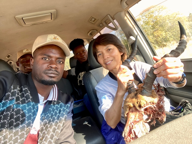 Group of people in a vehicle holding animal horns.