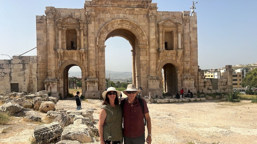 Couple standing in front of a historical archway.