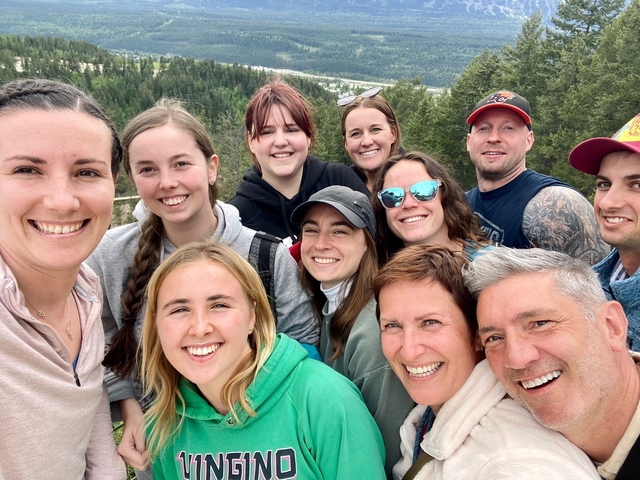       Group selfie with smiling faces and forest in the background.
  
