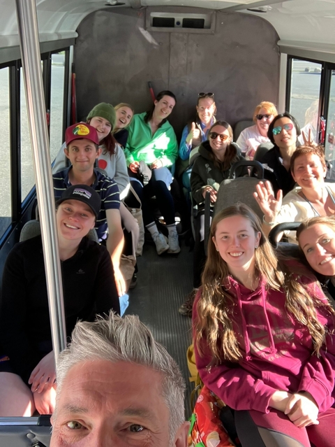 Bus interior with people smiling and waving at the camera.