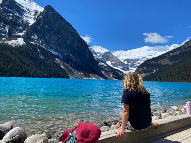 Person sitting by the edge of a stunning turquoise lake.