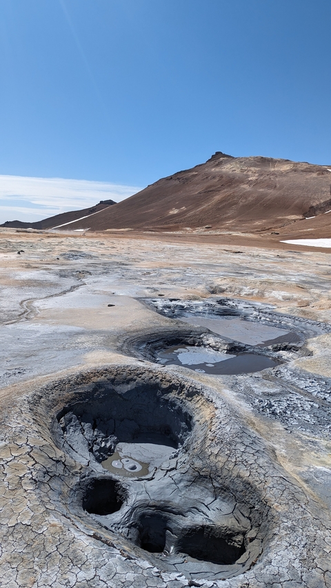 Volcanic landscape with steaming geothermal features.