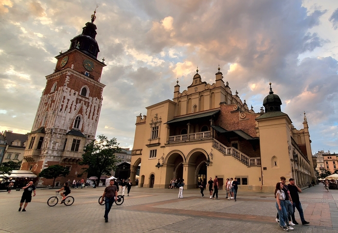       Historic building and tower in a busy city square.
  