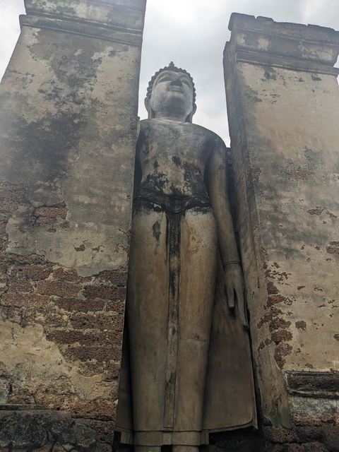       Tall ancient statue in temple ruins with weathered stone.
  