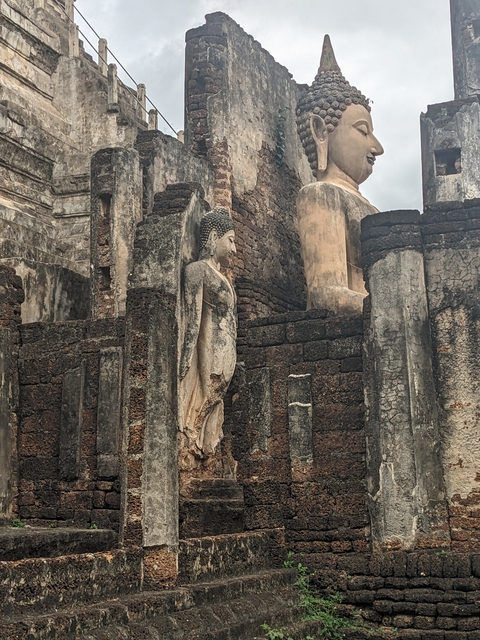       Weathered stone Buddha statue integrated into ancient ruins.
  