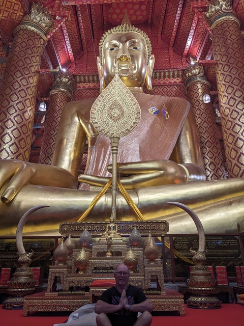      Large golden Buddha statue inside a richly decorated temple.
  