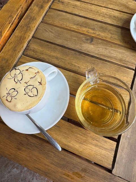 Cup of Vietnamese coffee with a glass of tea on a wooden table.