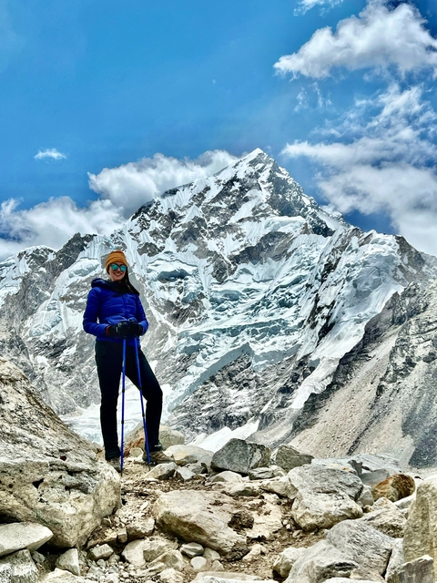 Hiker posing triumphantly against a snowy mountain backdrop.
