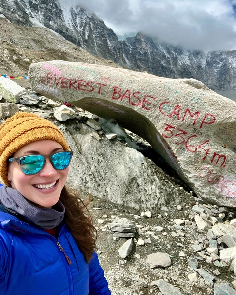 Traveler posing with a landmark sign at a base camp.