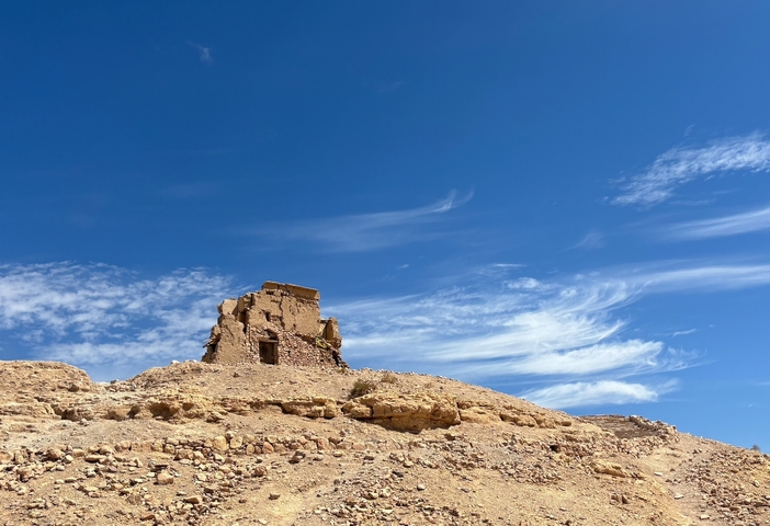 Ruins of a building on a hillside with a blue sky.