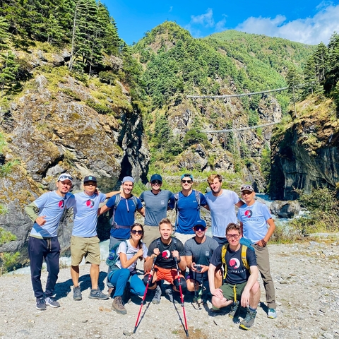       Group posing in front of a rugged mountain landscape.
  