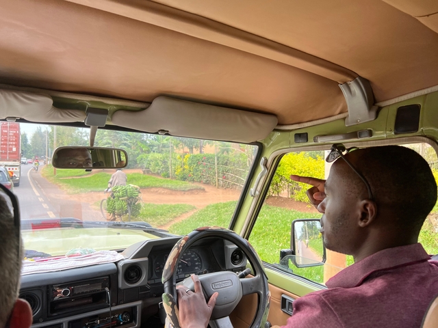 Man inside a vehicle pointing outside the window.