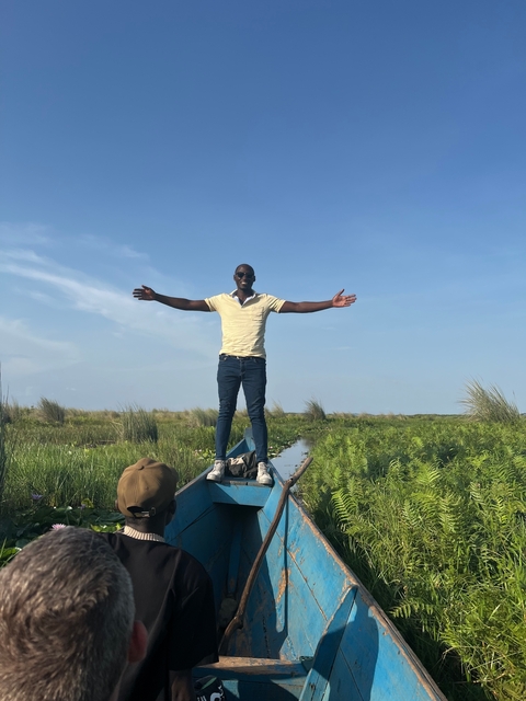 Man standing on a boat with arms outstretched.