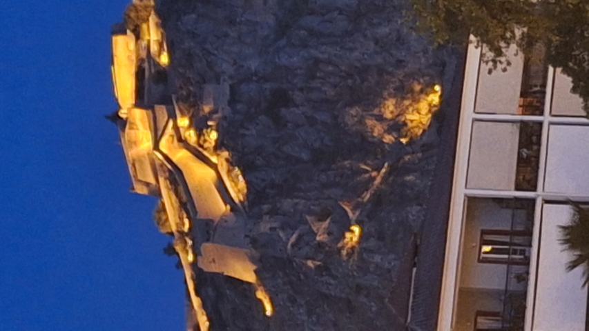       Lit up fortress on a hillside at night.
  