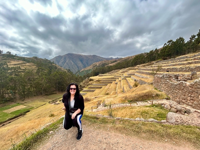       A woman standing near the terraced fields with a backdrop of mountains.
  