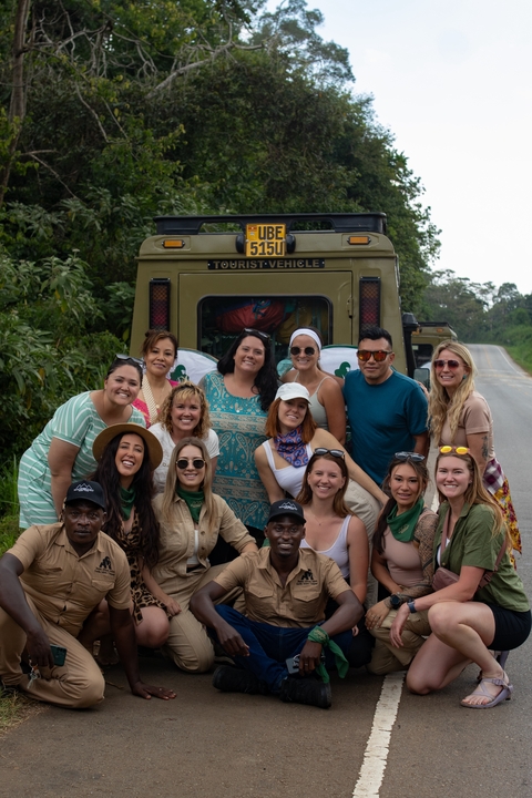 Group of people in front of a safari vehicle.