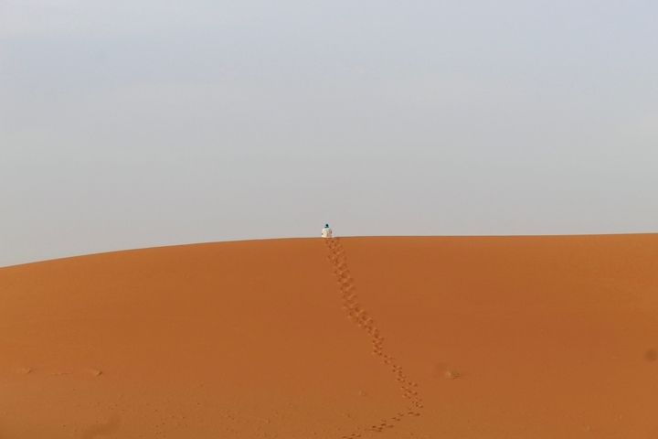 Vast sand dunes with person sitting on top.