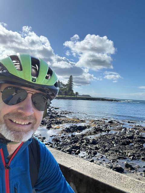 Person by rocky beach, wearing helmet and sunglasses.