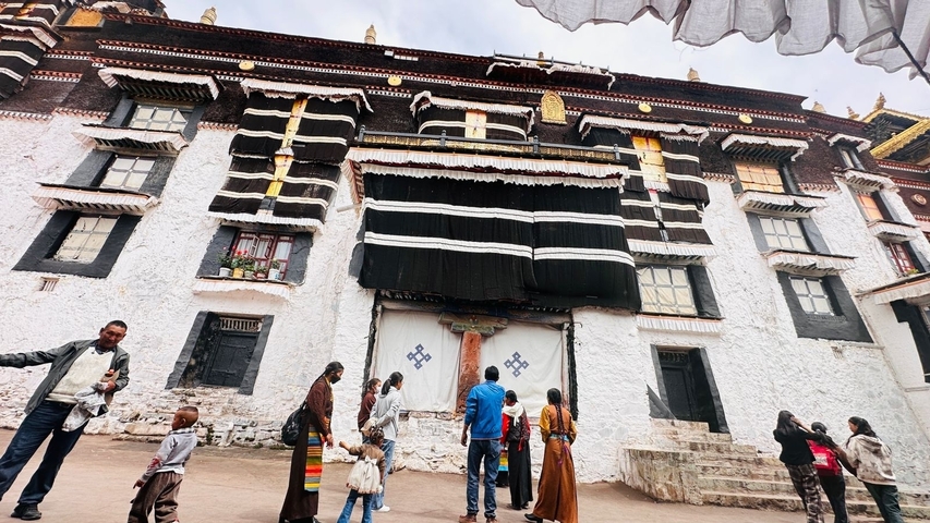 Group of people in front of a traditional Tibetan building.