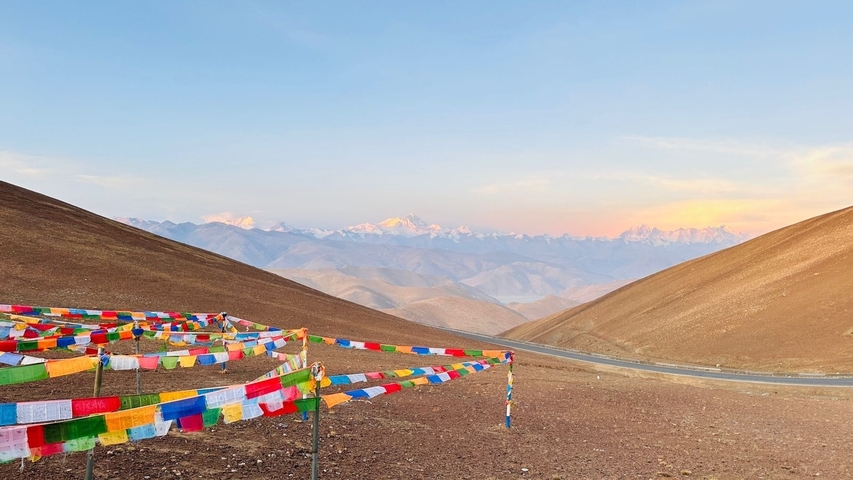 Prayer flags with a view of distant mountains during sunset.
