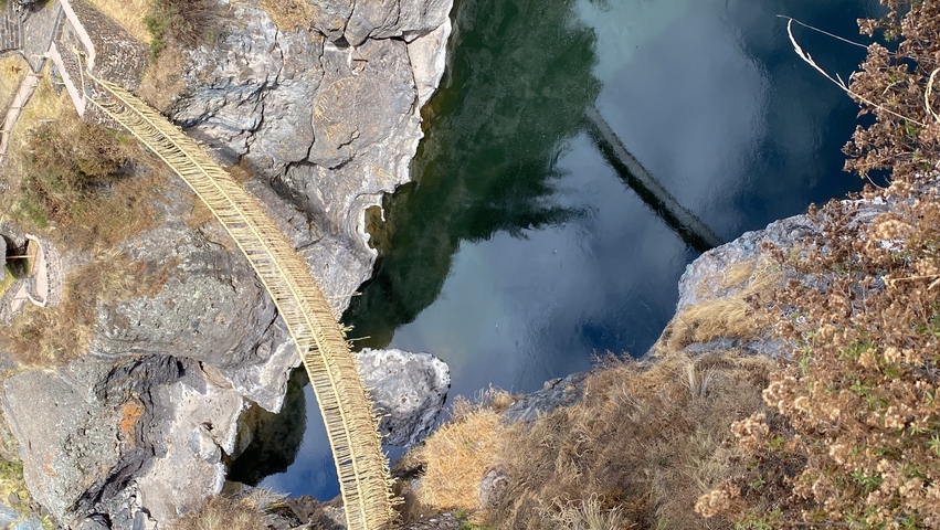       Wooden suspension bridge over a rocky river
  