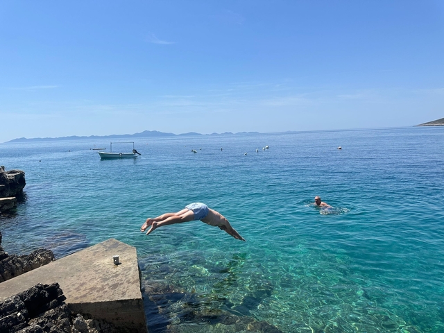       People swimming and diving in clear turquoise sea.
  