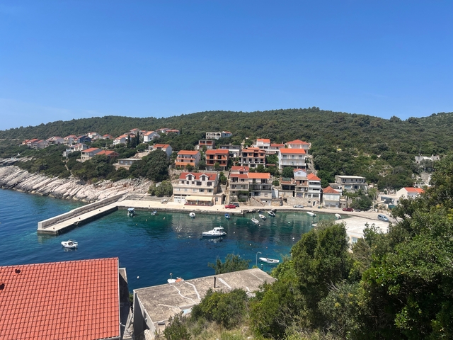       Coastal village with red-roofed houses and a harbor with boats.
  