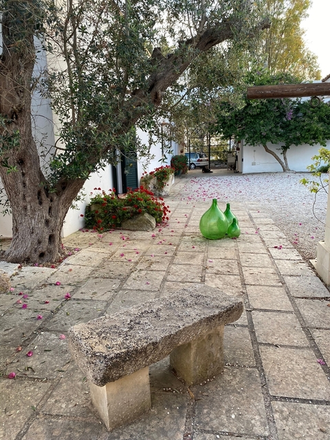       Outdoor courtyard with two large green glass vessels and flowers.
  