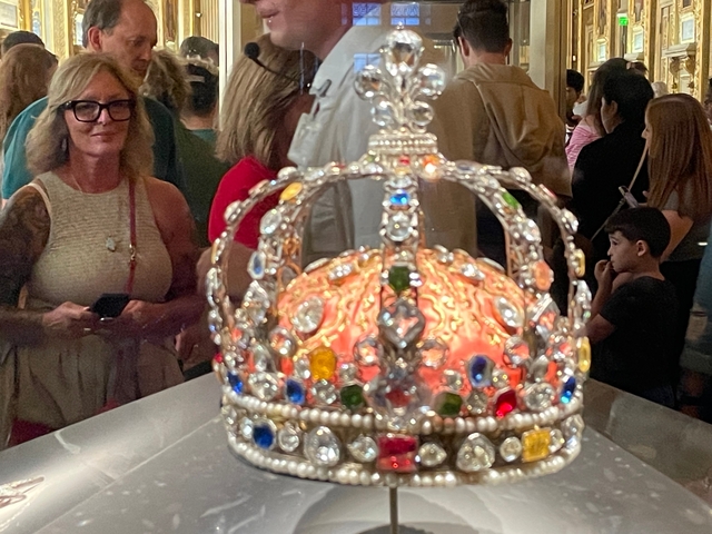 A crown displayed in a museum with people observing.