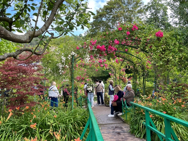       Tourists exploring a beautifully flowered garden pathway.
  