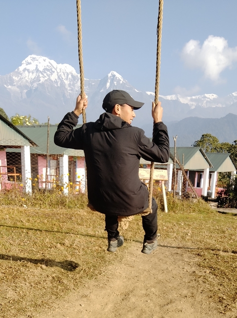Person swinging on a rope swing in a hilly area.