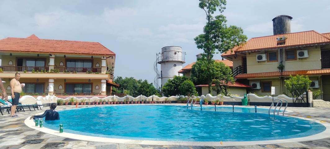 Outdoor swimming pool in a resort with greenery.
