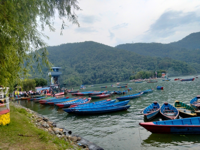       Colorful boats docked at a lakeshore with hills.
  
