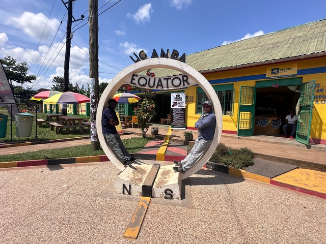 Two people posing at the Equator landmark in Uganda.