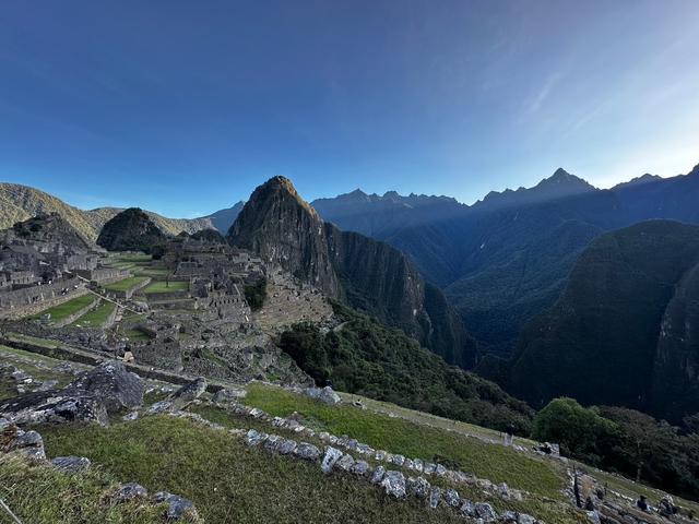 Machu Picchu ruins and mountains under clear sky.